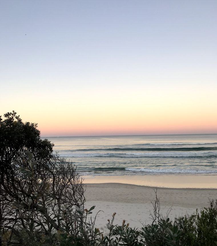 calm beach scene with flat ocean and beautiful sunset at Suffolk beach Byron