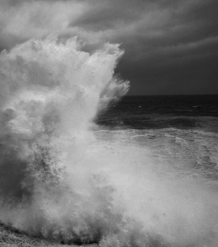 large wave hitting rocks with spray into the air